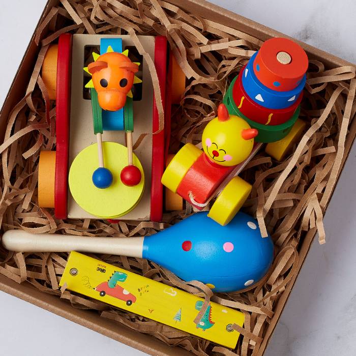 Close-up view of Baby's First Toy Set featuring vibrant wooden toys like a giraffe roller, stacking rings, maraca, and whistle. Ideal for toddlers.