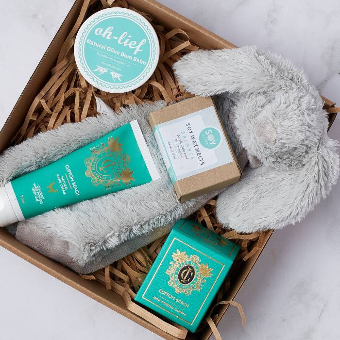 Close-up of Little Bundle of Joy Gift Box featuring baby balm, plush bunny, hand cream, candle, and wax melts.