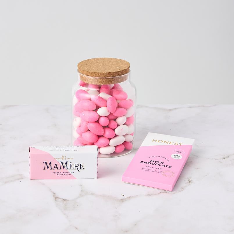 Candy Kisses Hamper featuring a jar of pink and white gourmet candies, MaMère nougat, and Honest artisan milk chocolate, beautifully arranged.