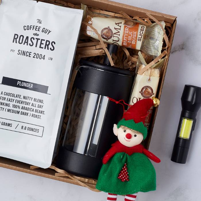 Christmas coffee gift box including a Coffee Guy coffee blend, French press, Ouma rusks, a flashlight, and a festive elf decoration.