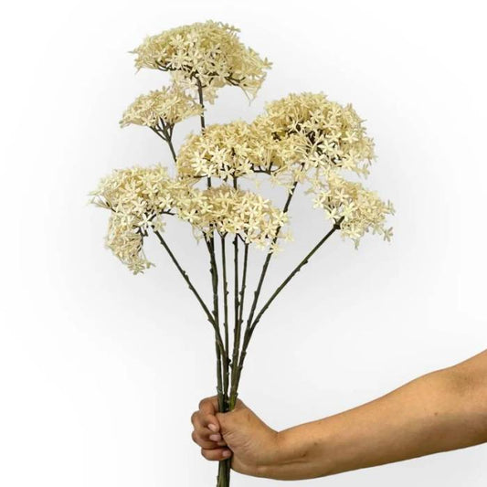 Hand holding a bouquet of Crown Spray Cream artificial flowers with multiple cream-coloured clusters on tall, slender stems.