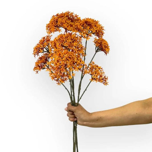 Hand holding a bouquet of Crown Spray Orange artificial flowers with vibrant orange clusters on tall, slender stems.