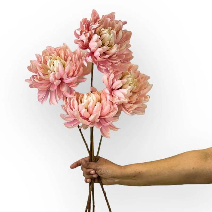 Hand holding a bouquet of Dahlia Mum Pink artificial flowers with large, soft pink blooms and multiple stems.