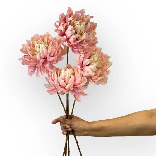 Hand holding a bouquet of Dahlia Mum Pink artificial flowers with large, soft pink blooms and multiple stems.