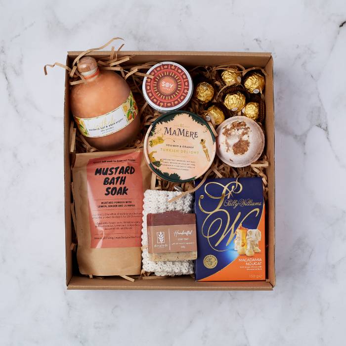 Deluxe Pamper Gift Box showcasing a selection of luxury self-care items including Turkish delight, bath salts, handmade soap, a mustard bath soak, Ferrero Rocher chocolates, and a soy candle, beautifully arranged in a gift box with natural filler.