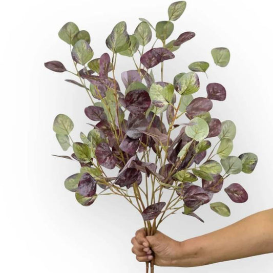 A hand holding a full bouquet of Eucalyptus Green Burgundy artificial foliage, highlighting the rich mix of green and burgundy leaves for a lush, lifelike display.