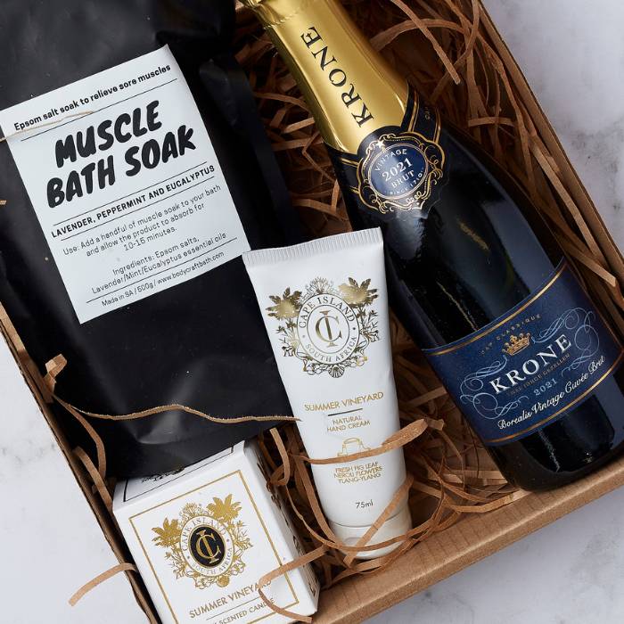 Close-up of the Krone & Calm Pamper Hamper showcasing a bottle of Krone MCC, bath soak, hand cream, and scented candle in elegant packaging.