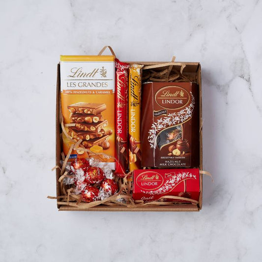 Lindt Lovers Gift Box by Flower Guy featuring Lindt Les Grandes bar, Lindor truffles, chocolate sticks, and hazelnut milk chocolate.