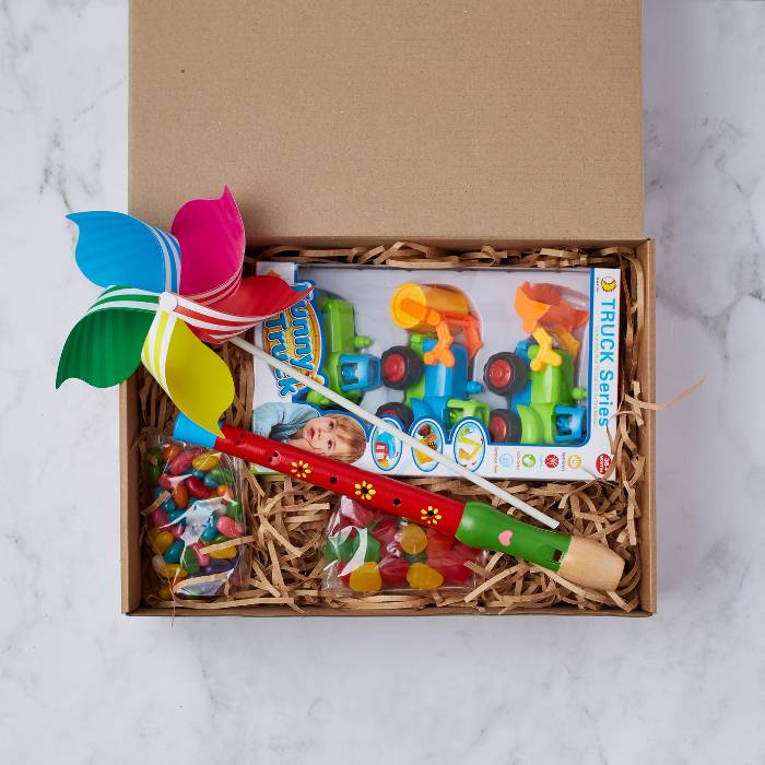 Little Builders Fun Kit with pinwheel, recorder flute, toy trucks, and jelly sweets in a gift box.