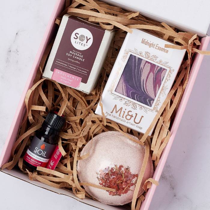 Close-up of Luxe Living Gift Box featuring artisan soap, massage candle, and deluxe bath bomb with rose petals.