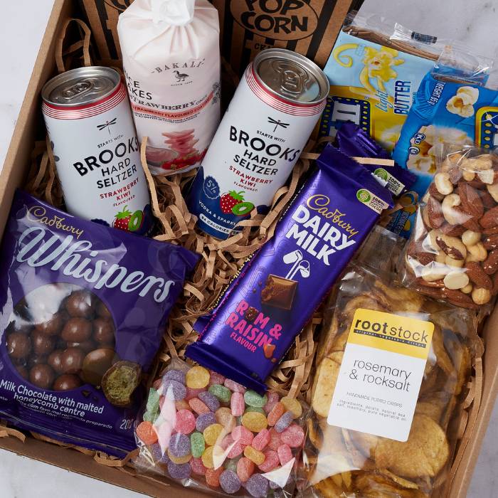 Close-up of Movie Night Box contents: Cadbury Whispers, jelly sweets, seltzers, chips, and popcorn tubs.