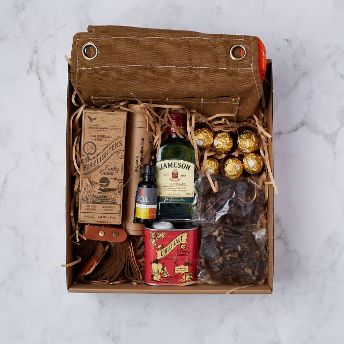 Outdoor Adventure Gift Box featuring Jameson whiskey, firelighters, chilli salt, leather braai accessories, and Ferrero Rocher chocolates.