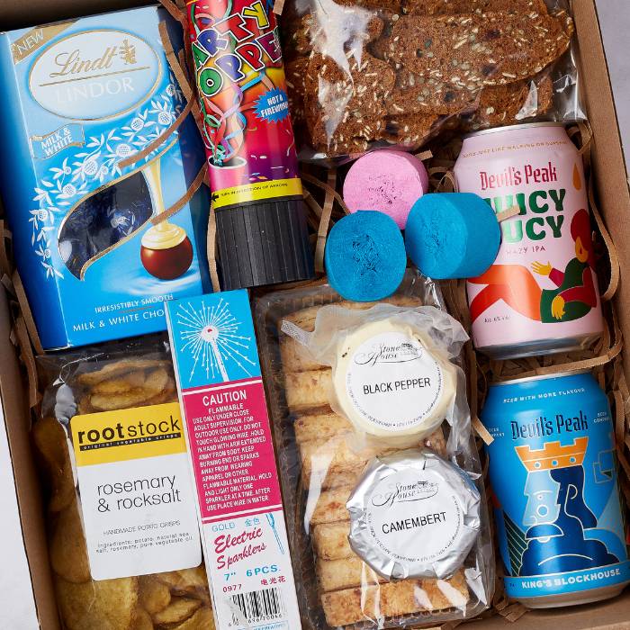 Close-up of Party Spark Gift Box featuring gourmet treats, craft beers, party poppers, and electric sparklers, ideal for gifting.