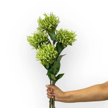 Hand holding a bouquet of Pincushion Green Artificial Flowers featuring multiple green spiky blooms and lush green leaves.