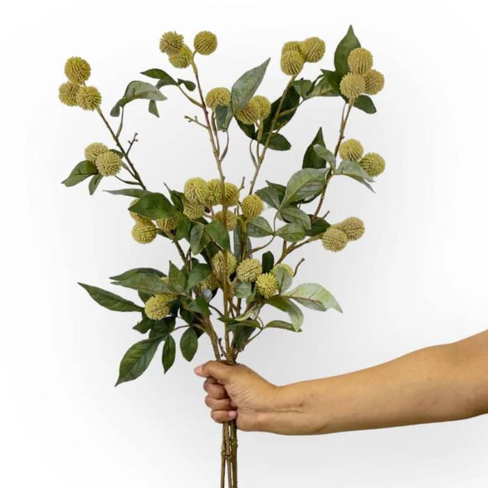 Hand holding a bouquet of Pom Pom Artificial Flowers with multiple stems of round green blooms and lush leaves.