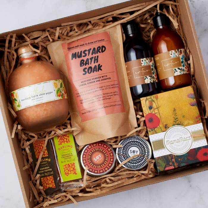 Close-up of Revitalise and Restore Gift Box featuring soy candles, gingerbread treats, and luxurious skincare items.