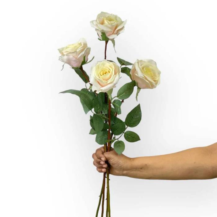 Bouquet of four Rose Olivia Seashell Artificial Flowers in full bloom, showcasing creamy white petals and lush green foliage, held in a hand for size reference