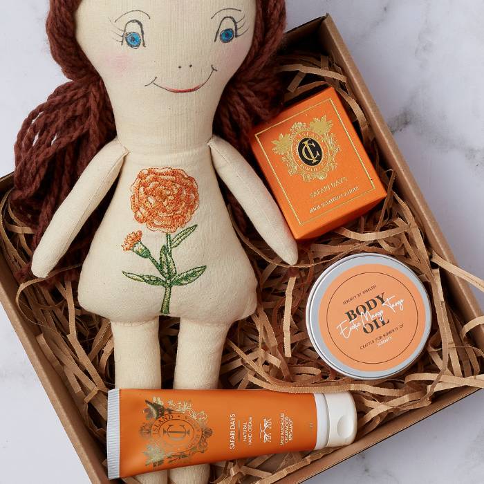 Close-up of Safari Dreams Gift Box contents: handcrafted doll, Safari Days candle, and luxurious pampering items.