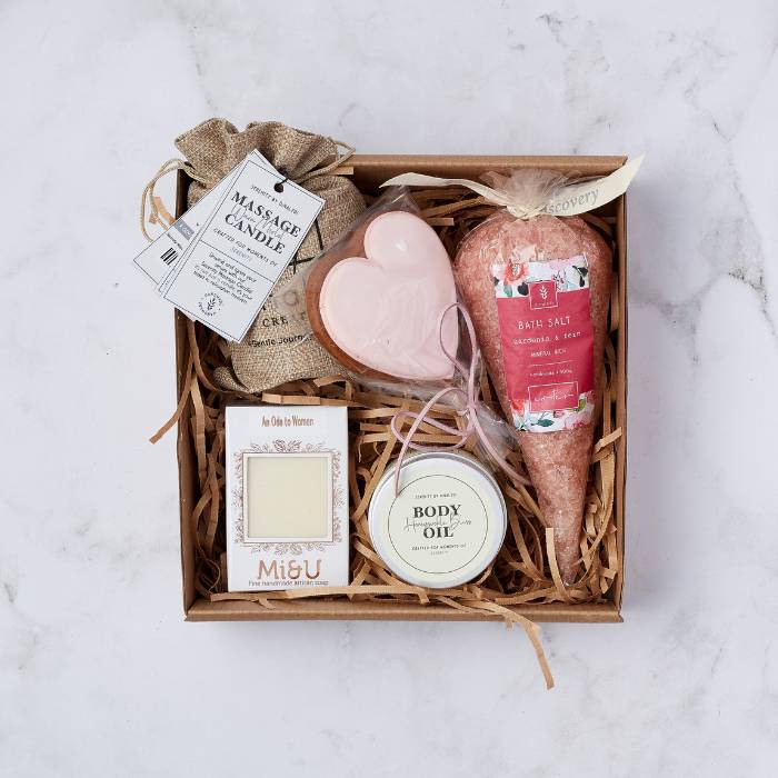 Spa Bliss Gift Box showcasing massage candle, bath salts, body oil, artisan soap, and a heart-shaped cookie.