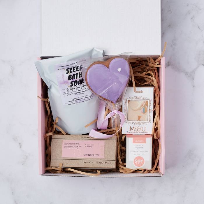 Sweet Dreams Gift Box contents including chamomile and lavender bath soak, heart-shaped biscuit, artisan soap, soy candle, and floral candles arranged in a gift box.