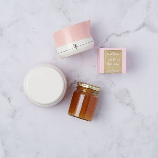 Flat lay of the Sweetheart Gift Set featuring a handcrafted ceramic milk mug, sugar pot, tutti frutti bonbons, and artisanal jam on a marble background.