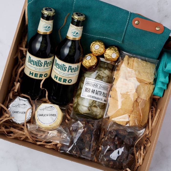 Close-up of the Tasting Adventure Gift Box showcasing Devil’s Peak Hero beers, bread and butter pickles, and Ferrero Rocher chocolates.