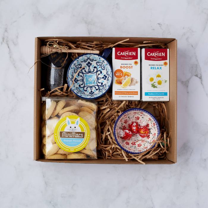 Tea Time Treat gift box containing Carmien Rooibos tea, artisanal honey jar with dipper, Mini Macs vanilla biscuits, and two colourful ceramic bowls, elegantly presented in a brown box with natural filler.