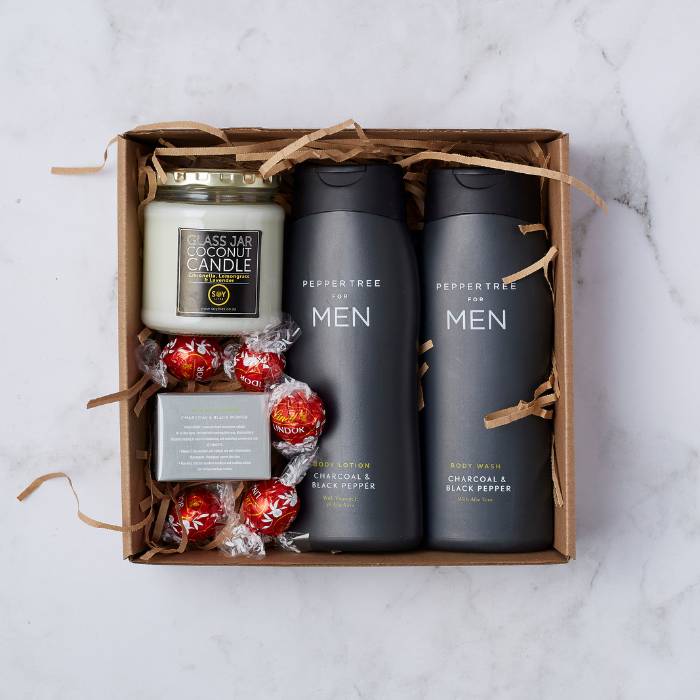 The Gentleman’s Essentials Gift Box by Flower Guy featuring body wash, body lotion, candle, soap bar, and Lindt chocolates.